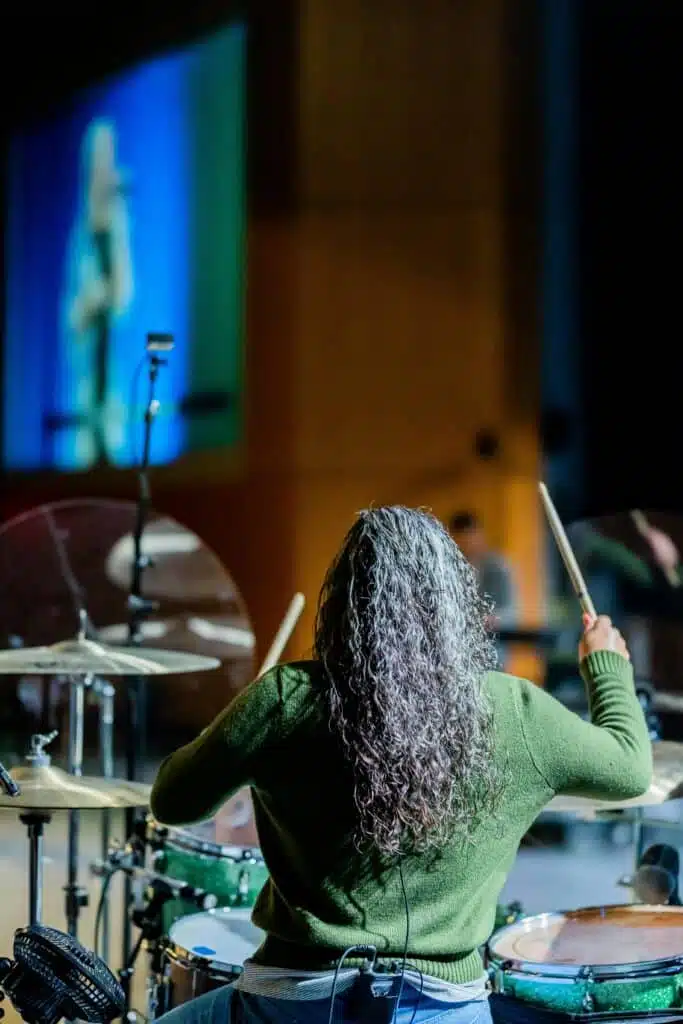 female drummer playing drum kit at concert 