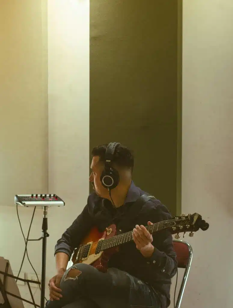 Guitarist sitting down and recording in studio 