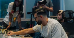 Group of young audio engineers working together at a professional mixing console inside Bay Eight Studio, adjusting sound levels and reviewing notes during a collaborative recording session in a state-of-the-art music production environment.