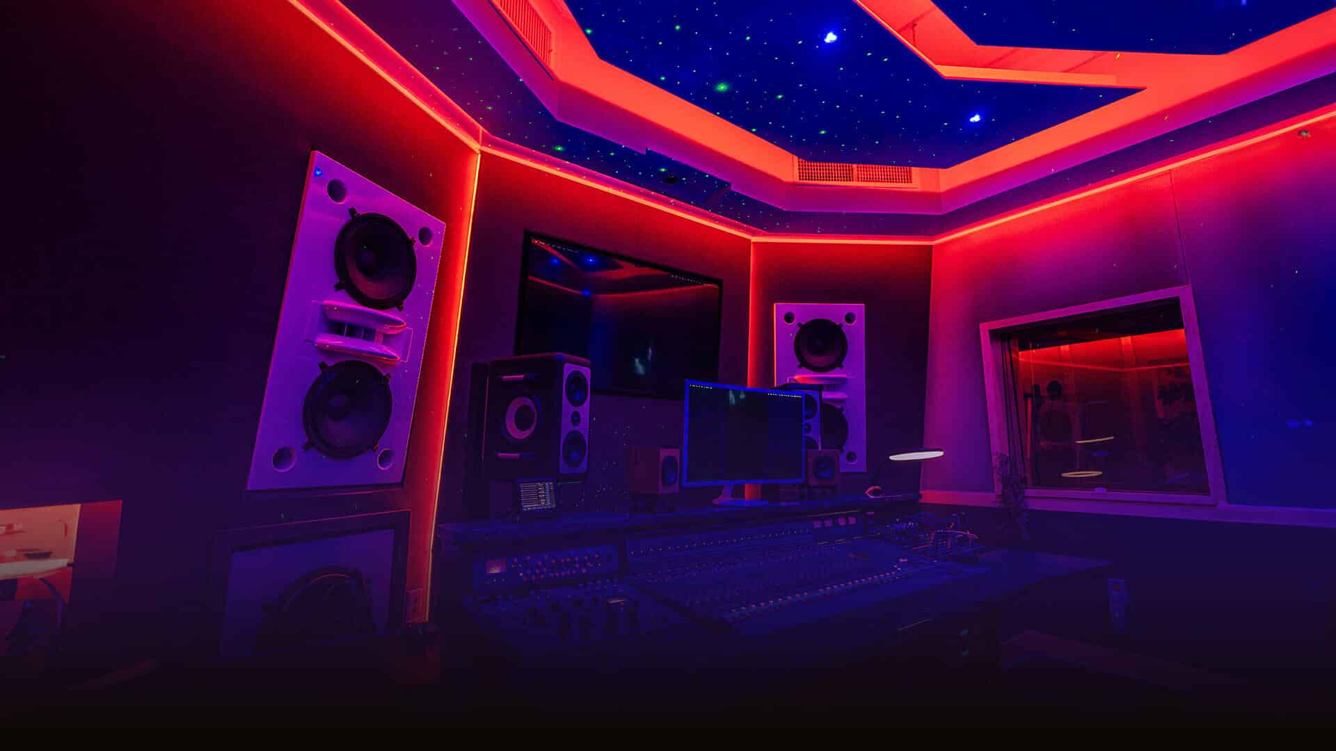 A visually stunning recording studio with a high-tech sound mixing desk, large speakers, and vibrant red and purple LED lighting. The ceiling is adorned with a starry sky effect, providing an immersive and creative environment. Ideal for anyone looking to rent a recording studio for a professional audio experience.
