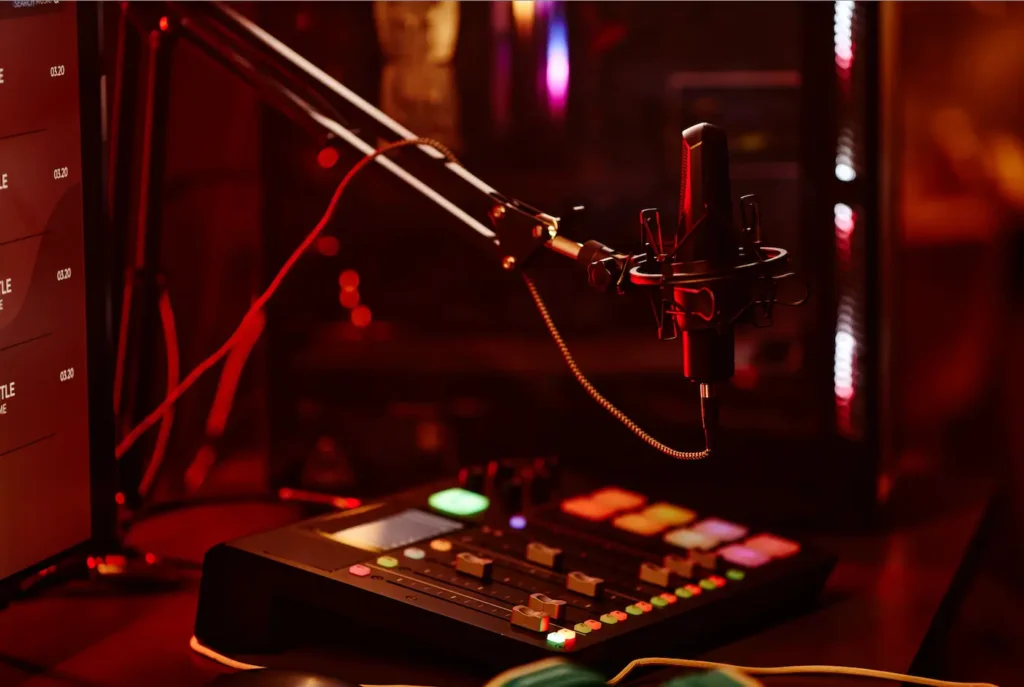 Close-up of a microphone setup and a digital audio mixing control panel, with vibrant lighting illuminating the scene. This image showcases the precise equipment needed for audio recording, perfect when you rent a recording studio to create high-quality sound projects.